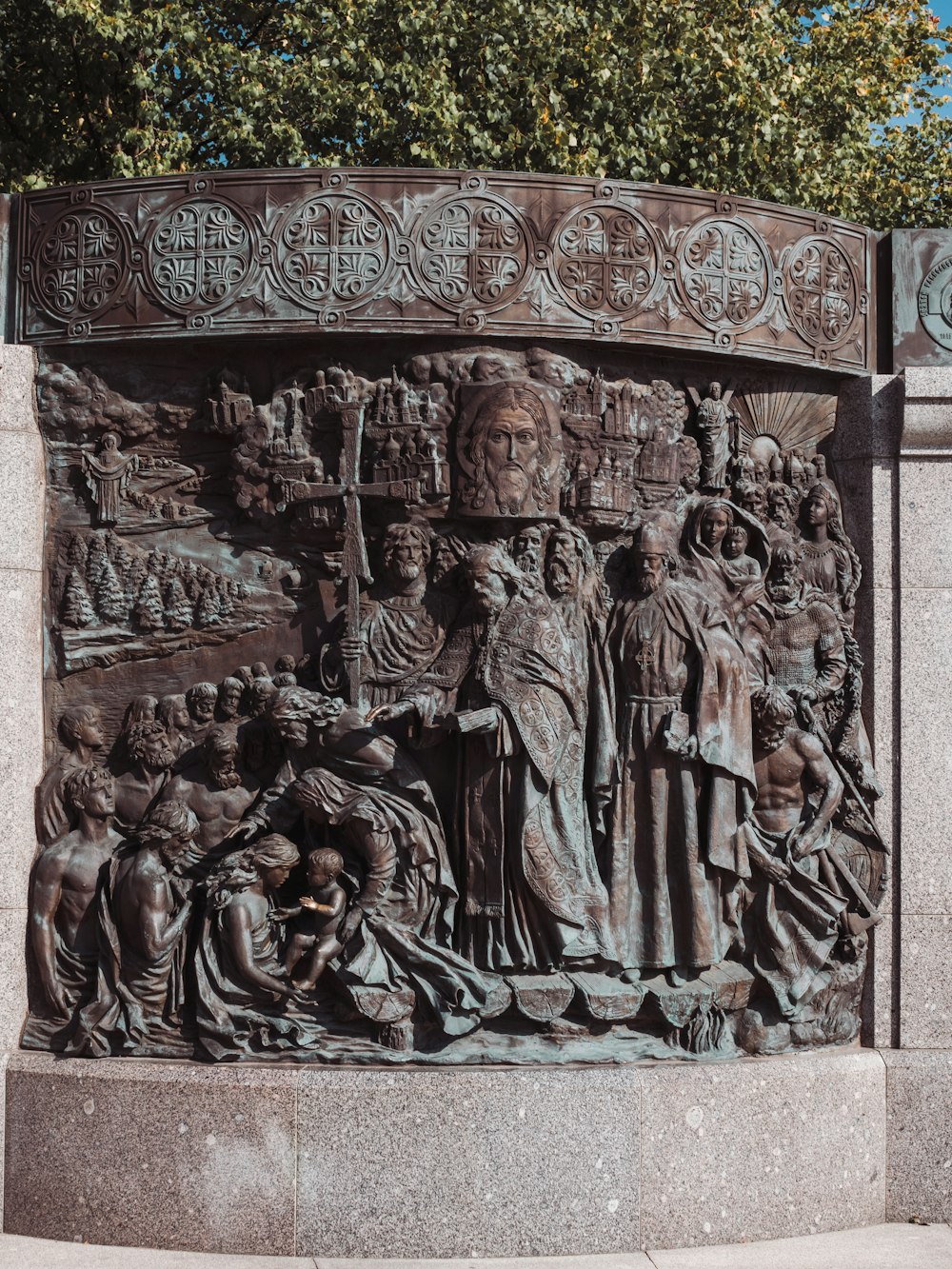 a statue of a group of people in front of a tree