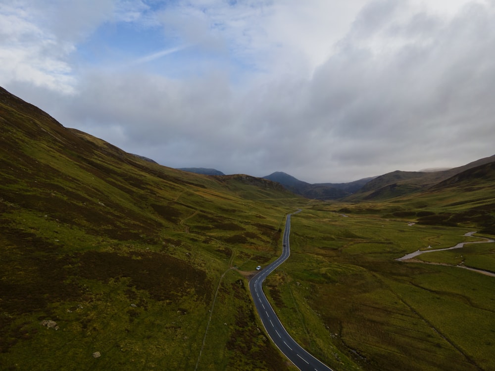 a winding road in the middle of a green valley