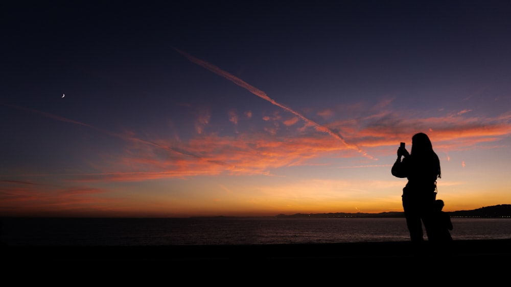 a person taking a picture of a sunset with a cell phone