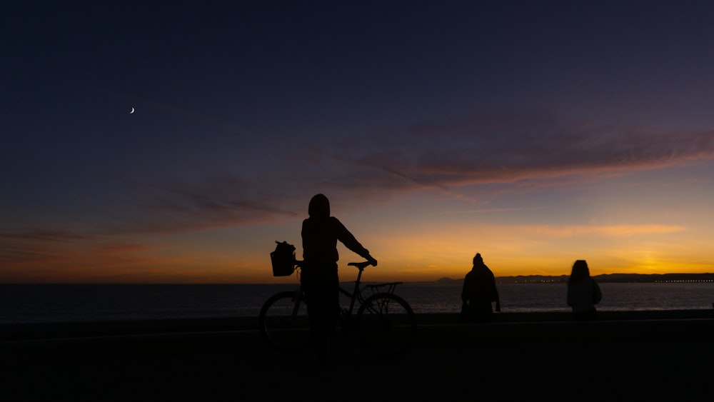 a person standing next to a bike near the ocean
