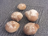 Rows of golden-brown bread rolls cooling on a rack in a bakery kitchen.