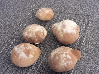 Rows of golden-brown bread rolls cooling on a rack in a bakery kitchen.
