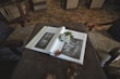 An open memory book filled with photos, notes, and mementos, resting on a cozy armchair.