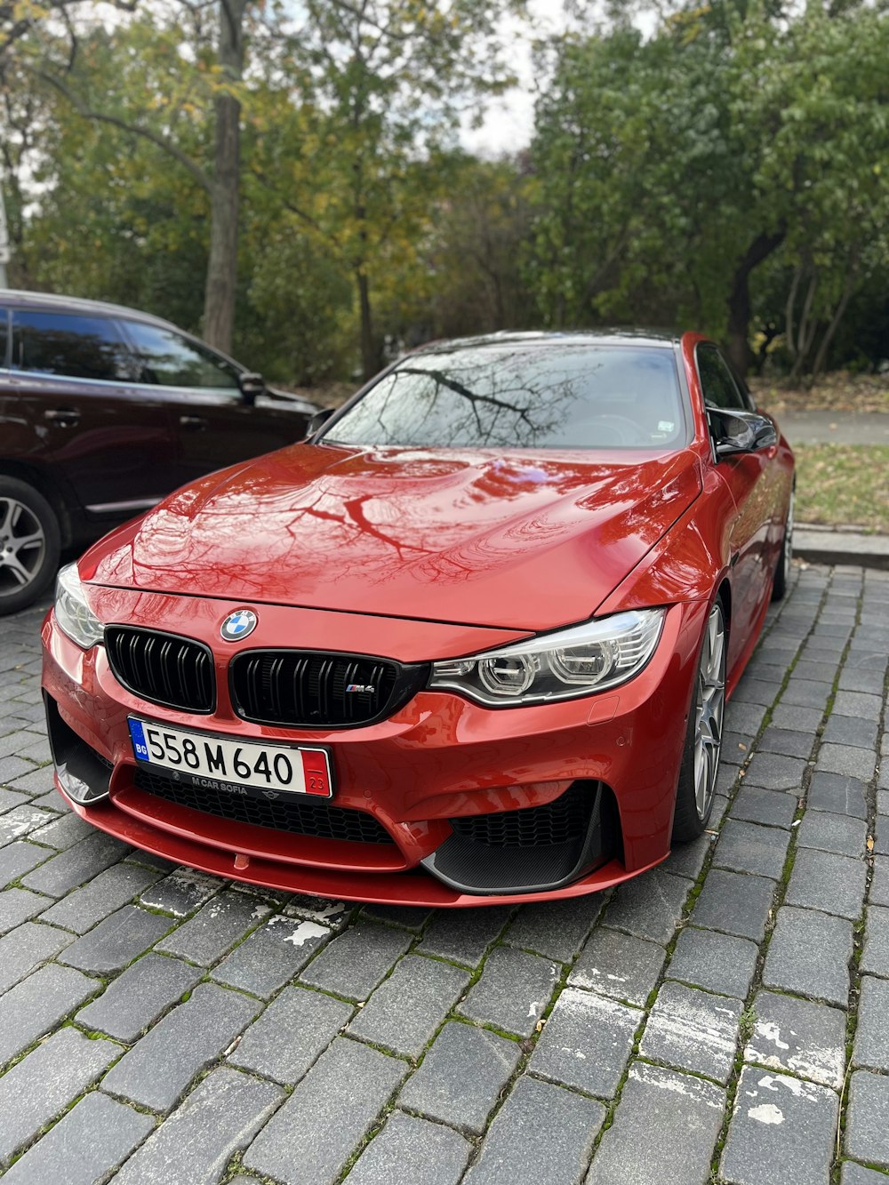 um carro vermelho estacionado ao lado de um carro preto