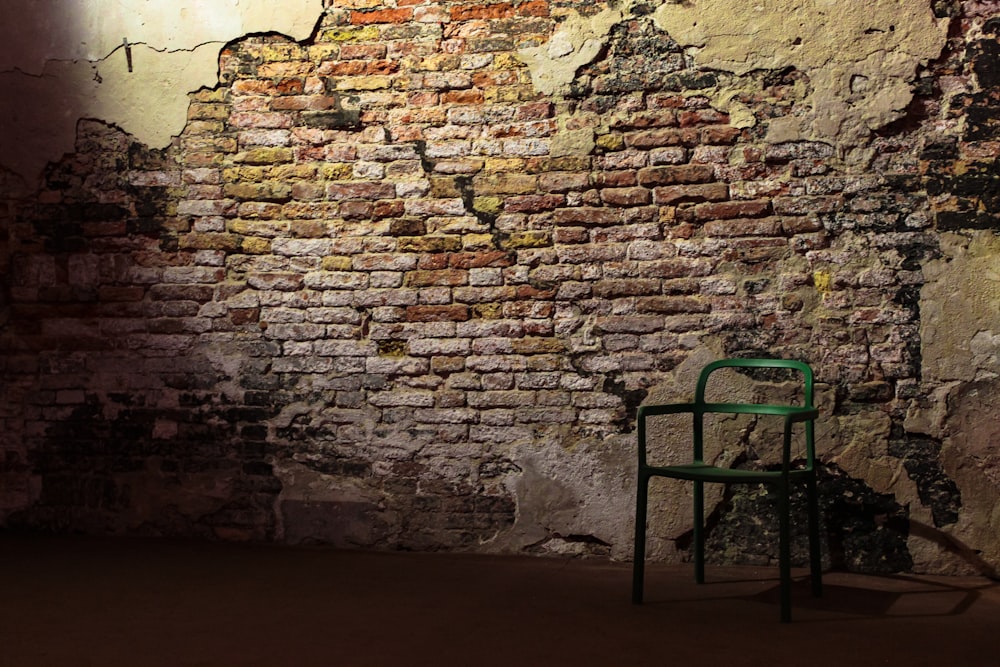a green chair sitting in front of a brick wall