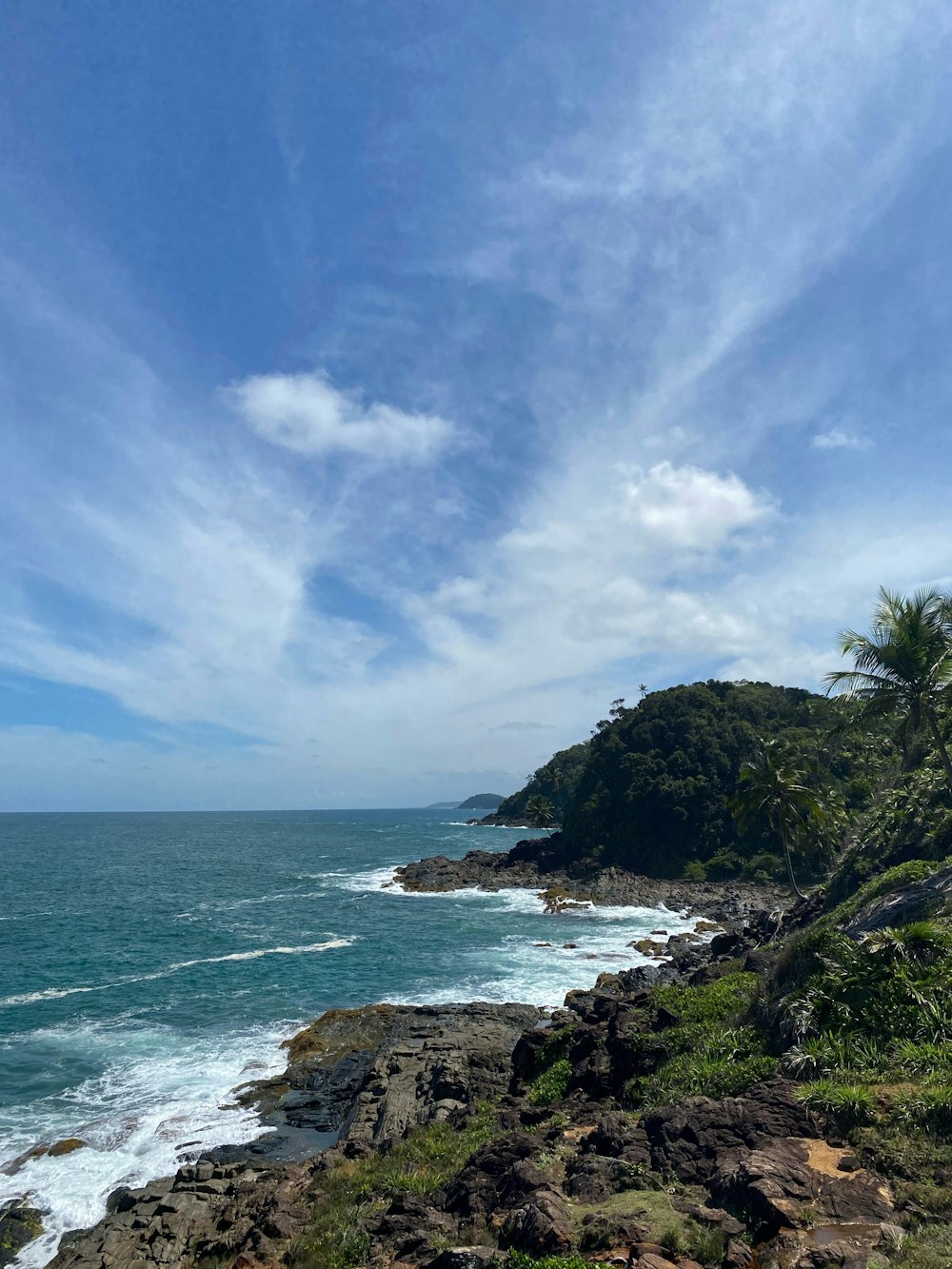 um banco sentado ao lado de um penhasco com vista para o oceano