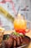 A plate of glazed ribs garnished with chopped green onions and white flowers is paired with a side of fries in a metal basket. In the background, a vibrant gradient drink in a mason jar with a straw features layers of orange, yellow, and red, styled with blueberries and a garnish.