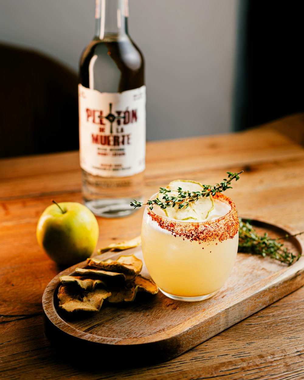 a wooden tray topped with a drink and crackers