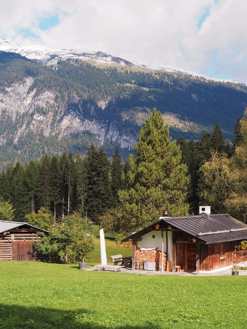 a cabin in the middle of a field with mountains in the background