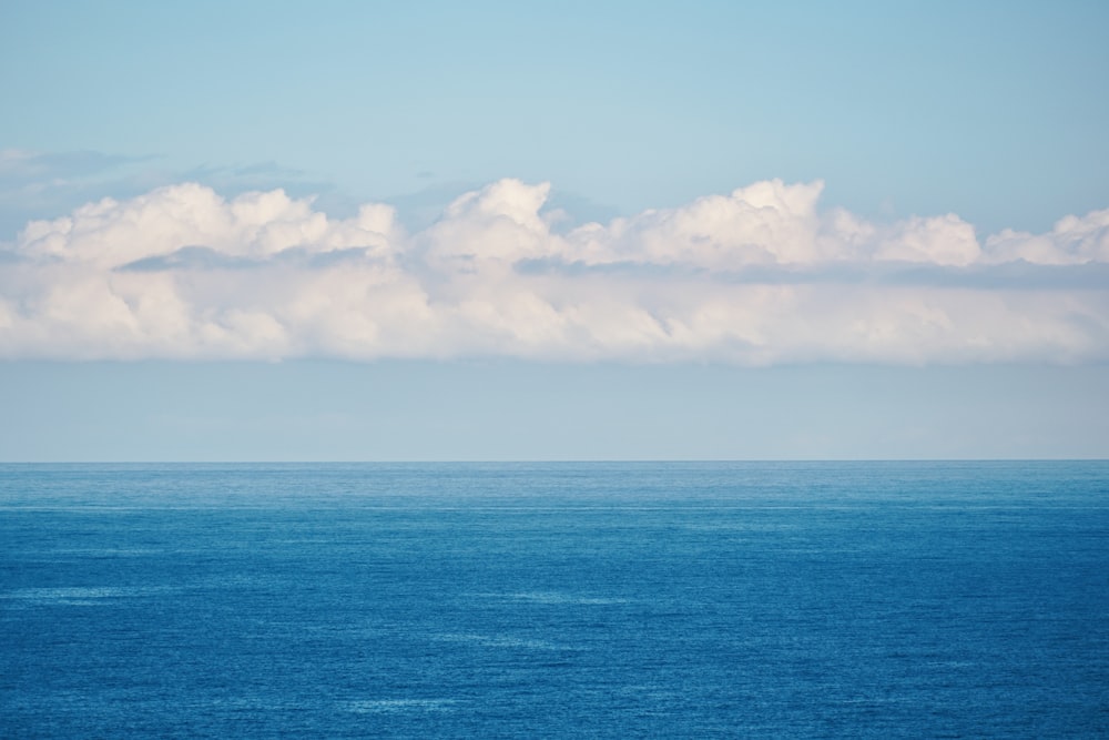 um grande corpo de água sentado sob um céu azul nublado