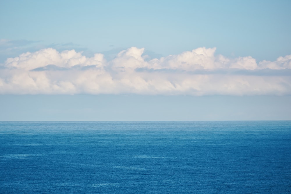 a large body of water sitting under a cloudy blue sky