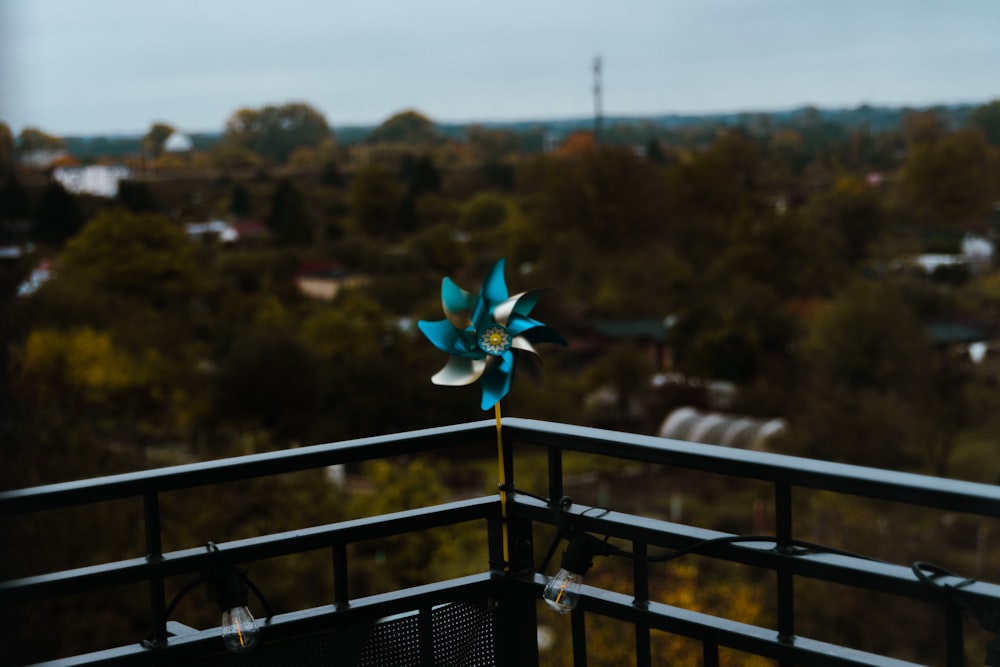 a blue pinwheel sitting on top of a metal fence