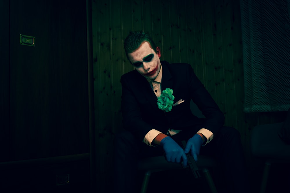 Ein Mann, der als Joker verkleidet auf einem Stuhl sitzt