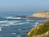 A panoramic shot of the coastline near Lima with surfers catching waves.
