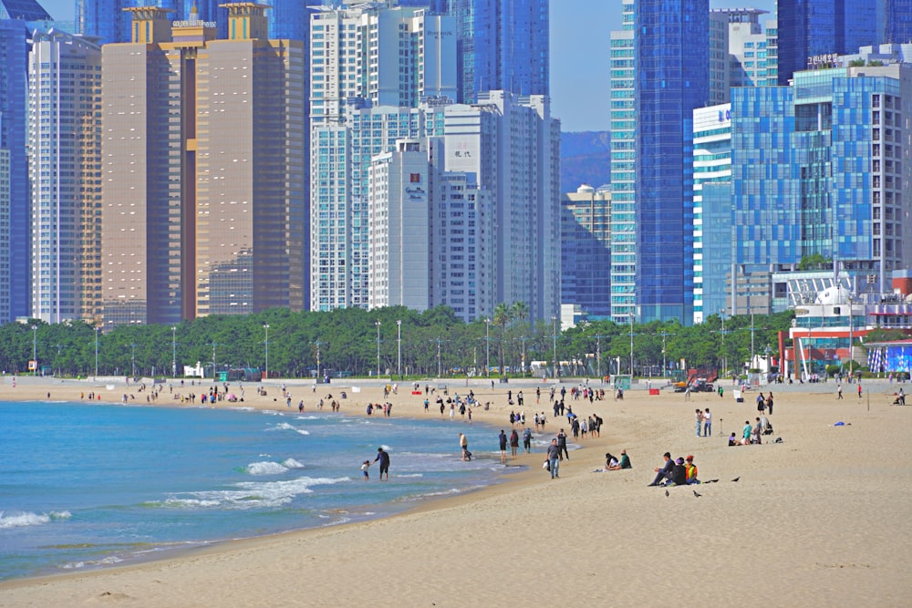 a crowded beach in front of a large city