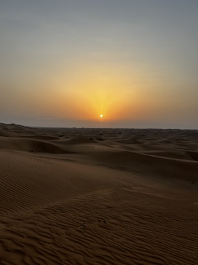 A serene Moroccan desert landscape with soft dunes and a golden sunset.