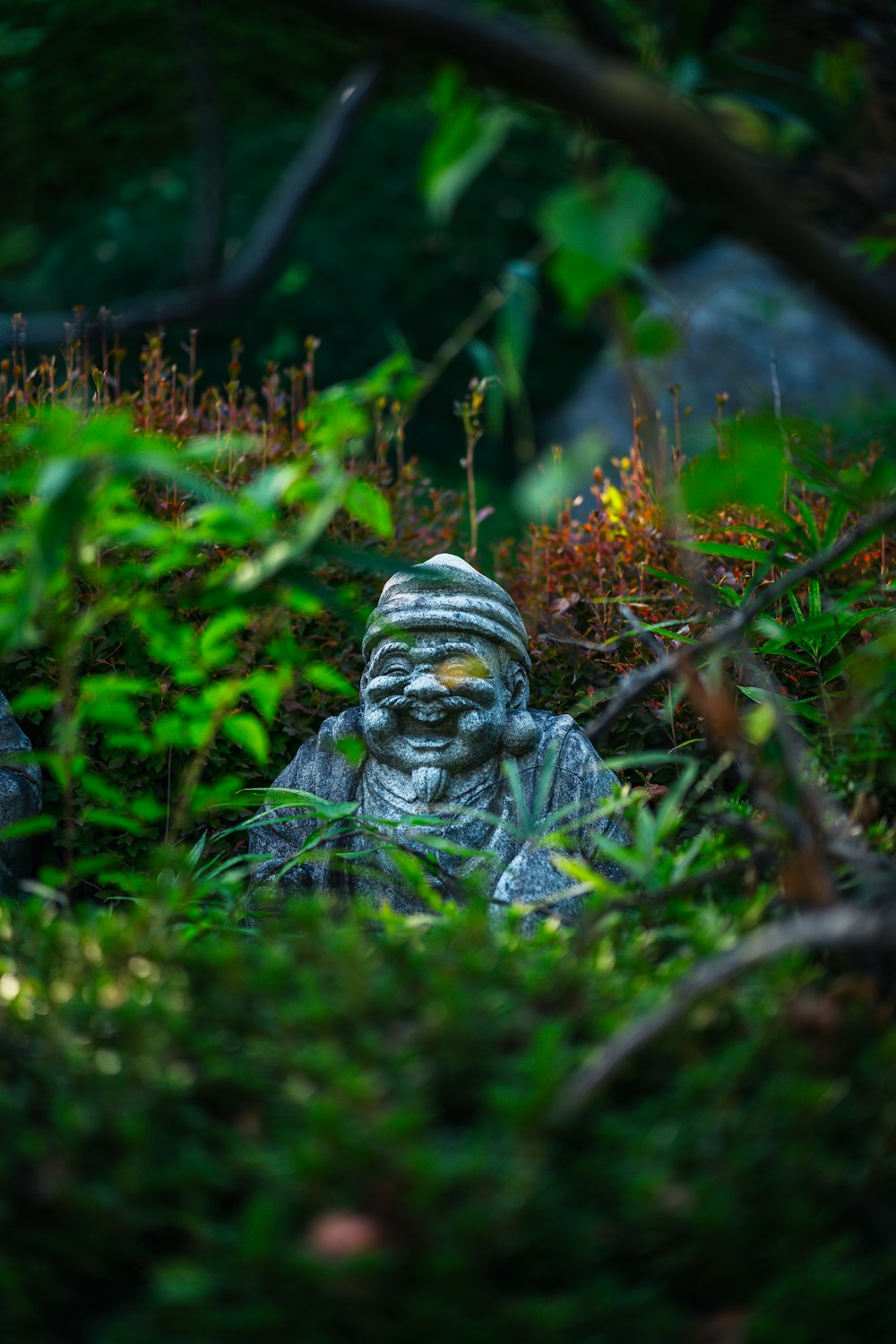 a statue sitting in the middle of a lush green forest