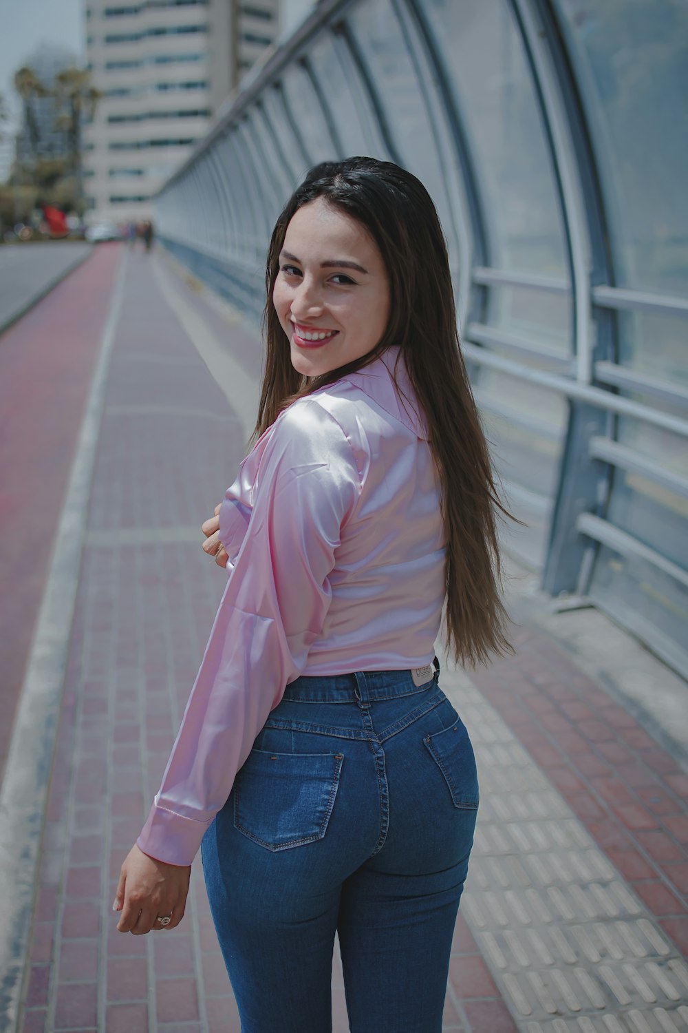 a woman in a pink shirt and jeans posing for a picture