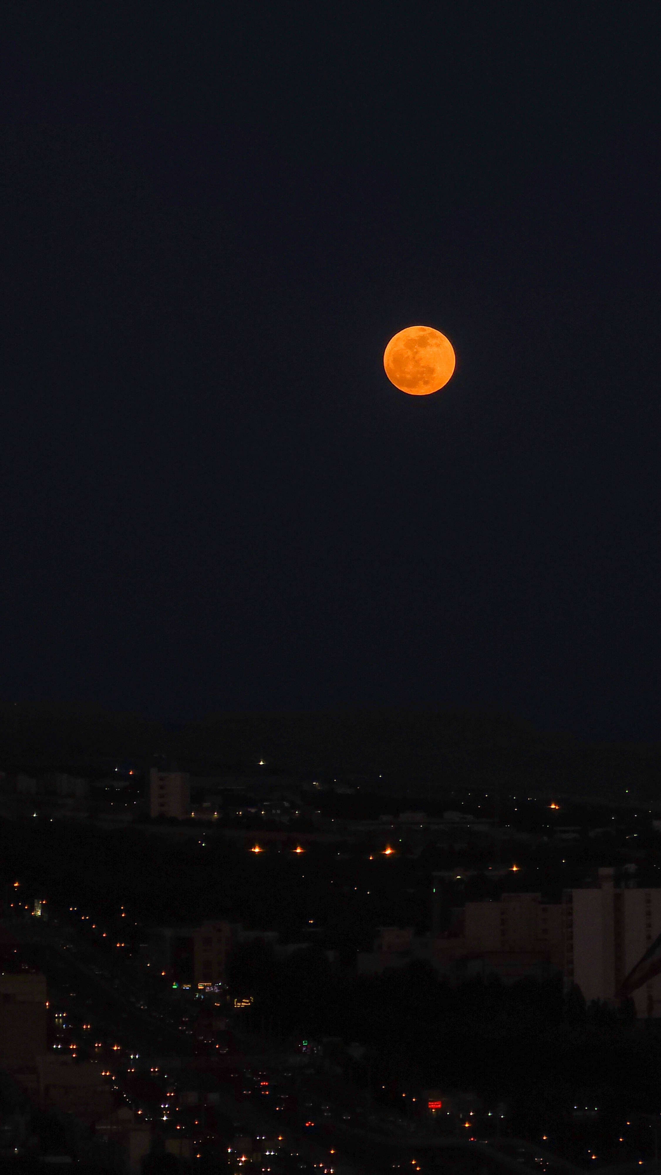 a full moon is seen over a city at night