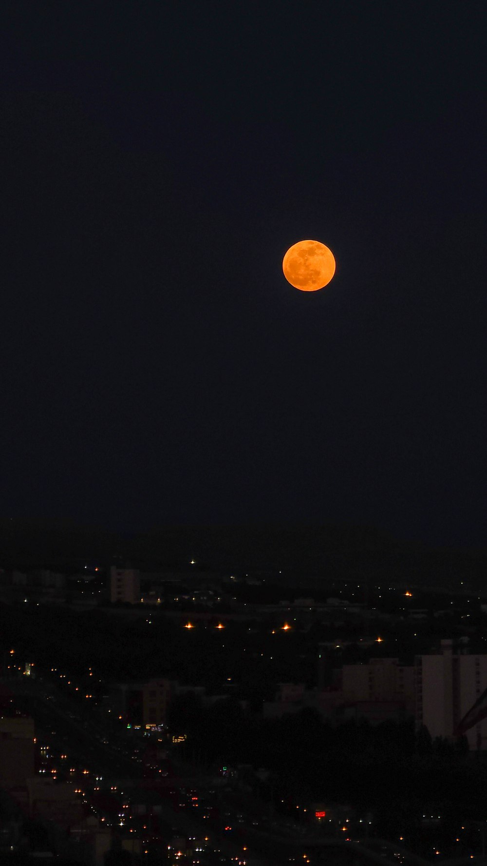 a full moon is seen over a city at night