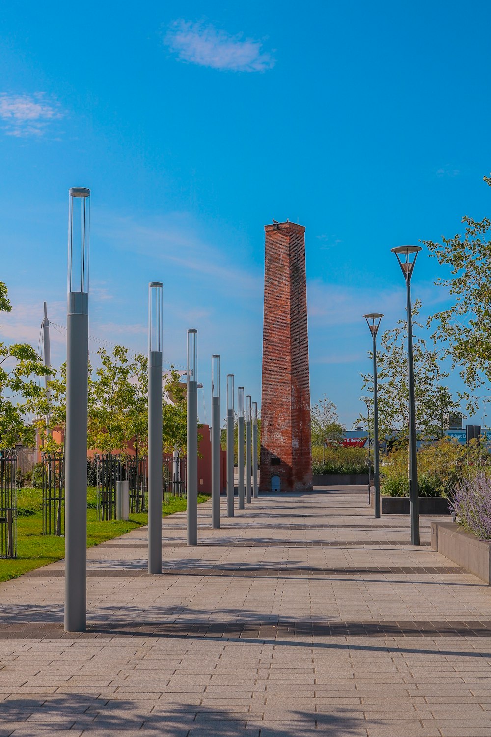 a walkway lined with metal poles and a brick tower in the background