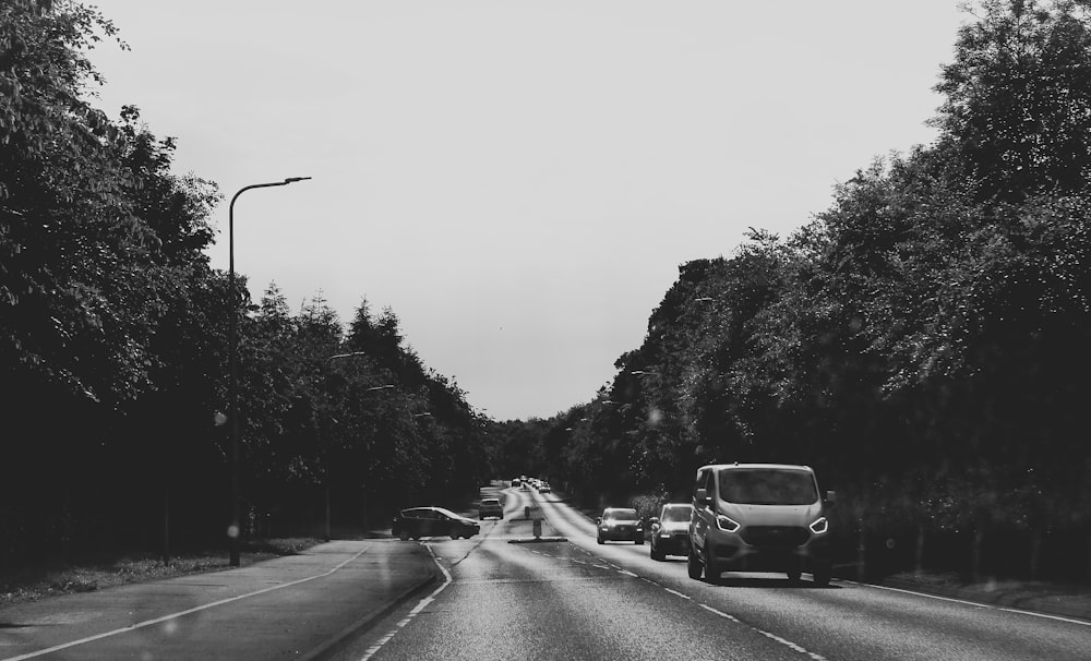a black and white photo of cars driving down a road