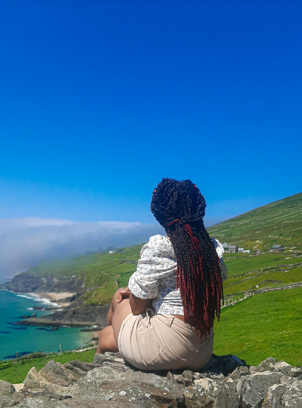 a woman sitting on top of a rock next to the ocean