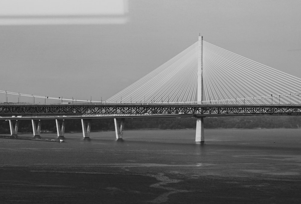 a black and white photo of a bridge over water