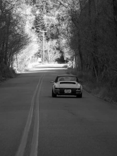 The 1930 Ford cruising along a quiet country road lined with tall trees.