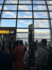 A traveler holding a boarding pass at an airport gate with a plane visible outside.