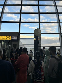 A traveler holding a boarding pass at an airport gate with a plane visible outside.