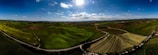 A panoramic view of rolling hills seen from a mountain bike path during a bright sunny day.