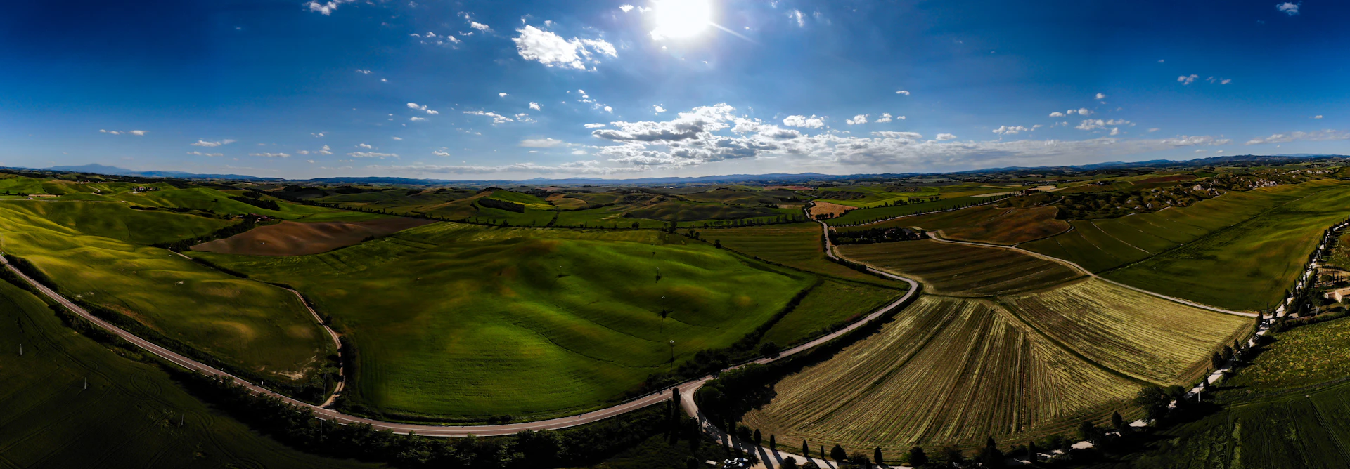 A panoramic view of well-laid roads connecting the lots, with distant hills and vibrant vegetation under a warm afternoon light.