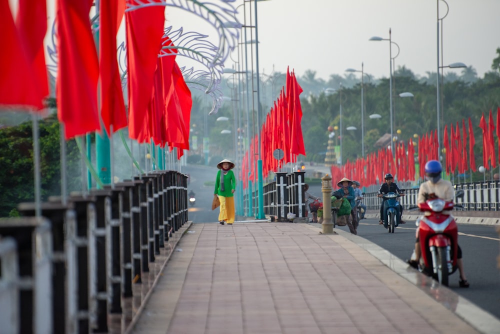 a man riding a motorcycle down a street next to red flags