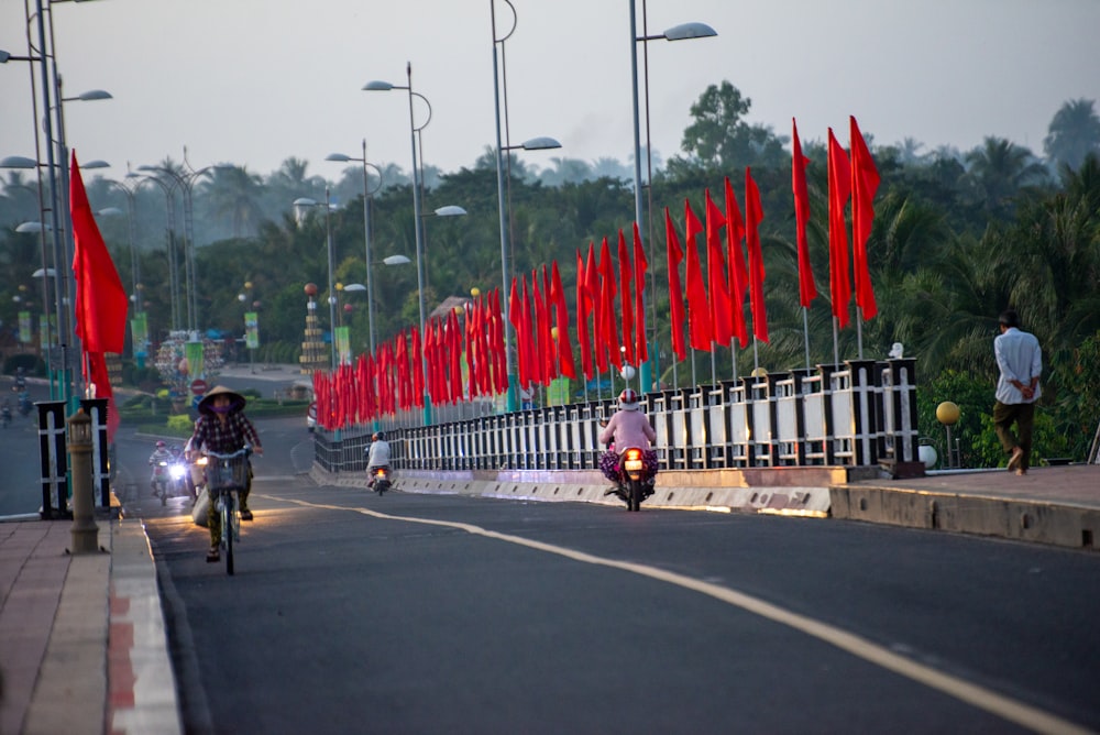 a man riding a motorcycle down a street next to red flags