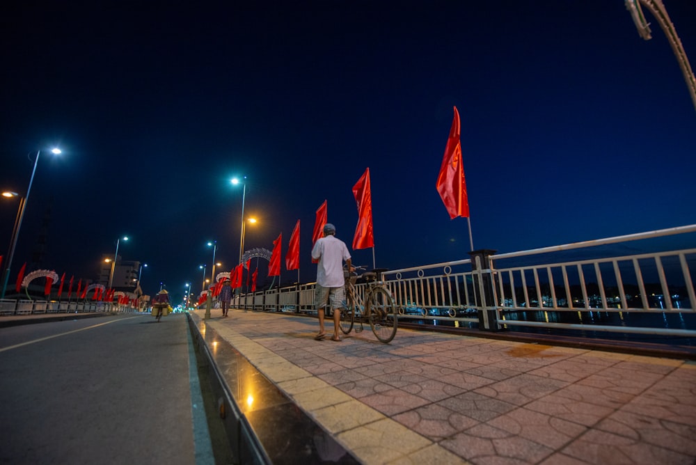 a man riding a bike down a street next to red flags