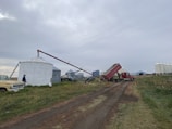 A delivery truck unloading bags of animal feed at a rural farm.