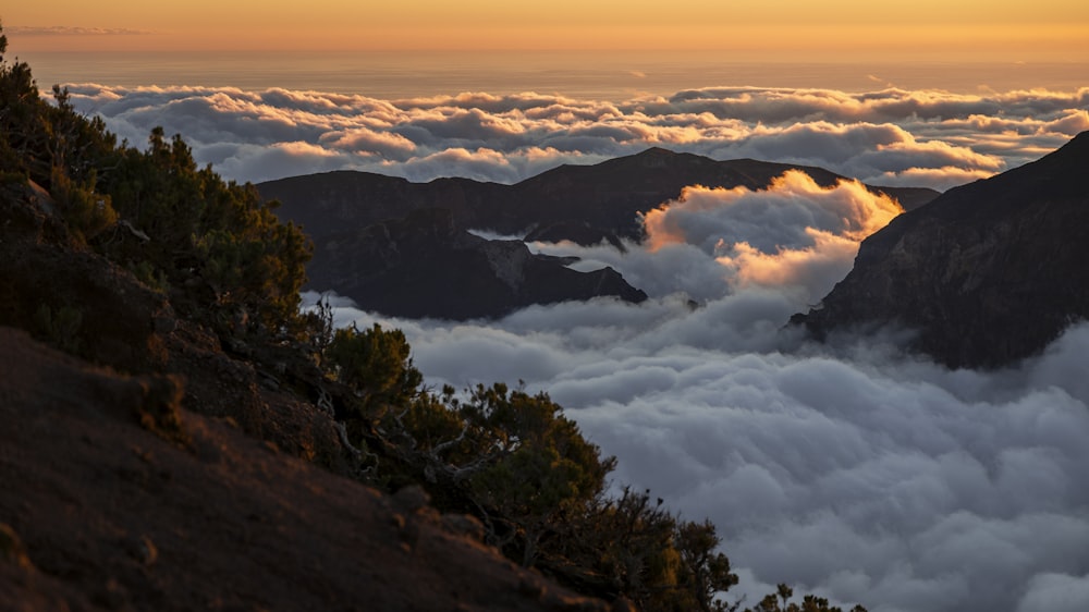 the sun is setting over the clouds in the mountains