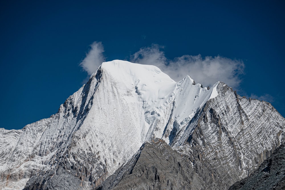 a snow covered mountain with a cloud in the sky