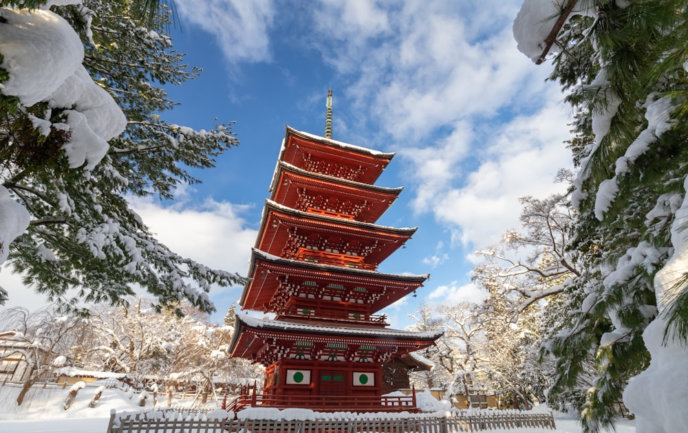 a tall red pagoda surrounded by snow covered trees