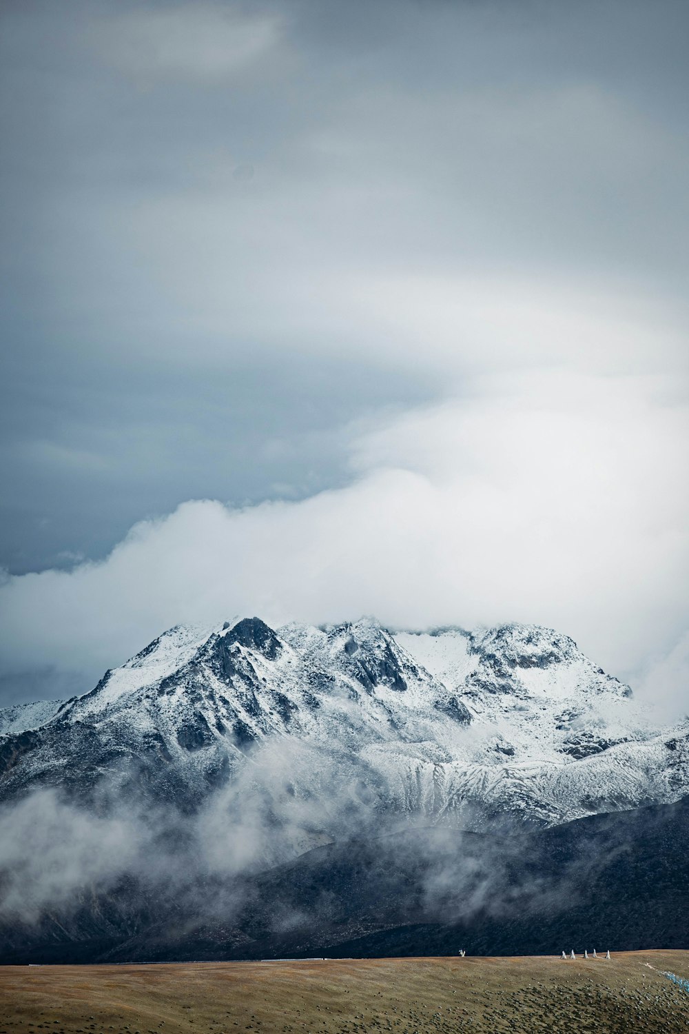 a large mountain covered in snow under a cloudy sky