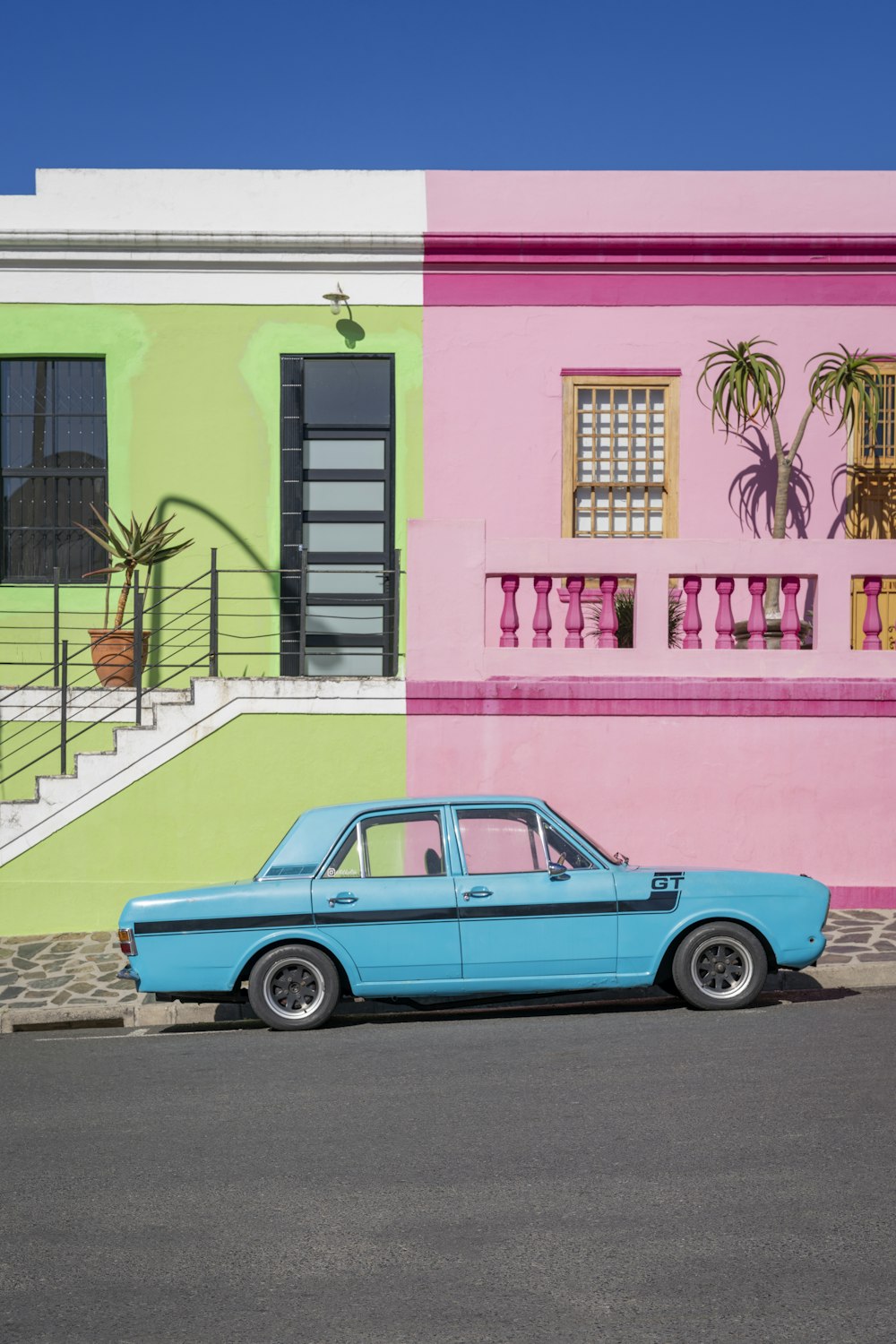 a blue car parked in front of a multi - colored building