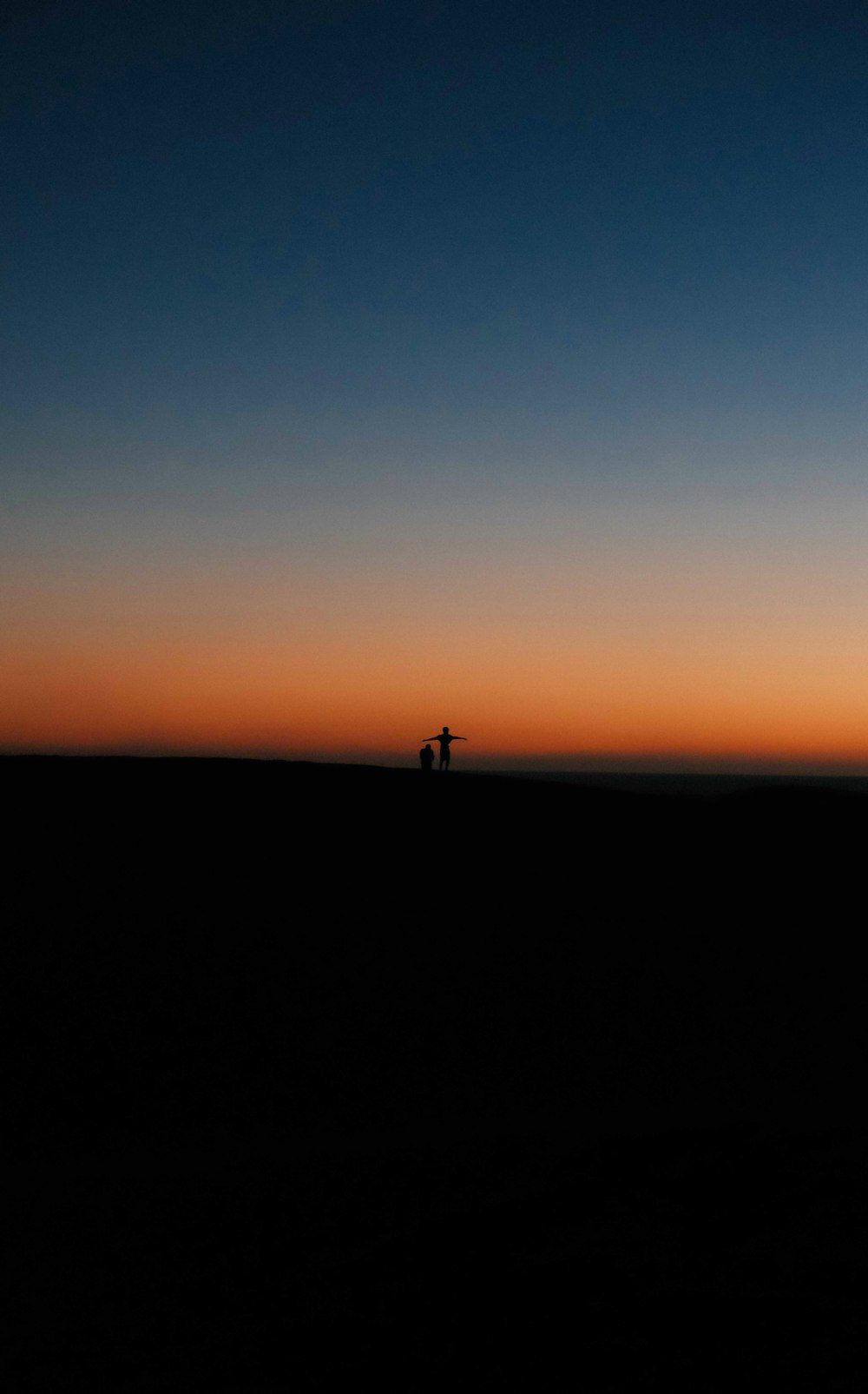 a couple of people standing on top of a sandy beach