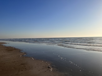 A serene beach scene with gentle ocean waves and soft natural sunlight highlighting elegant swimwear.