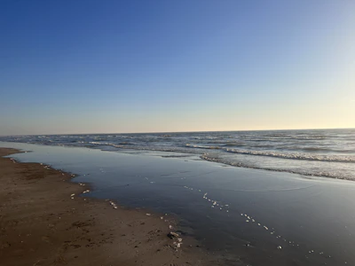 A tranquil beach scene with smooth waves and warm sunlight casting a peaceful glow on the sand.