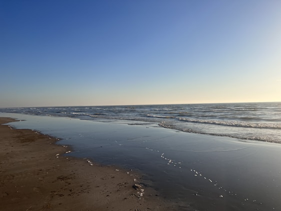 A serene beach scene with gentle ocean waves and soft natural sunlight highlighting elegant swimwear.
