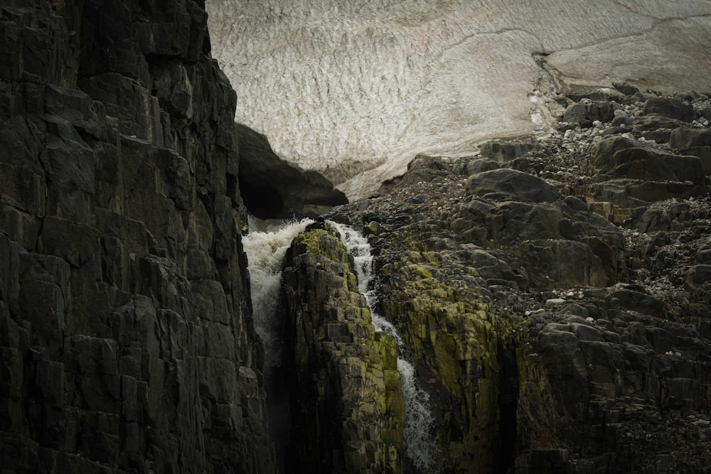 a waterfall is coming out of a crack in the rocks