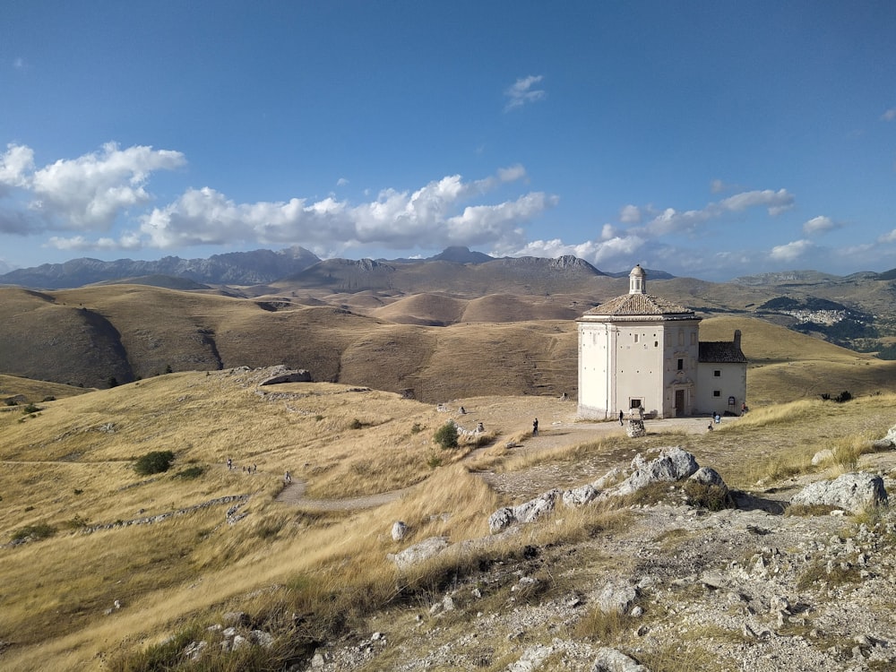 a white building on a hill with mountains in the background