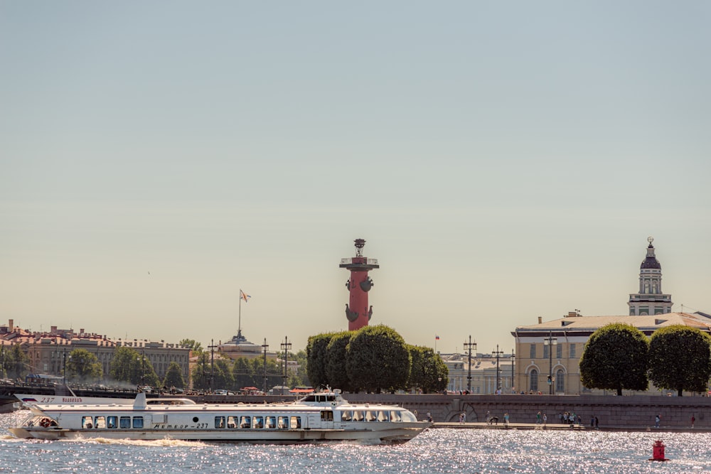 a white boat traveling down a river next to a tall building