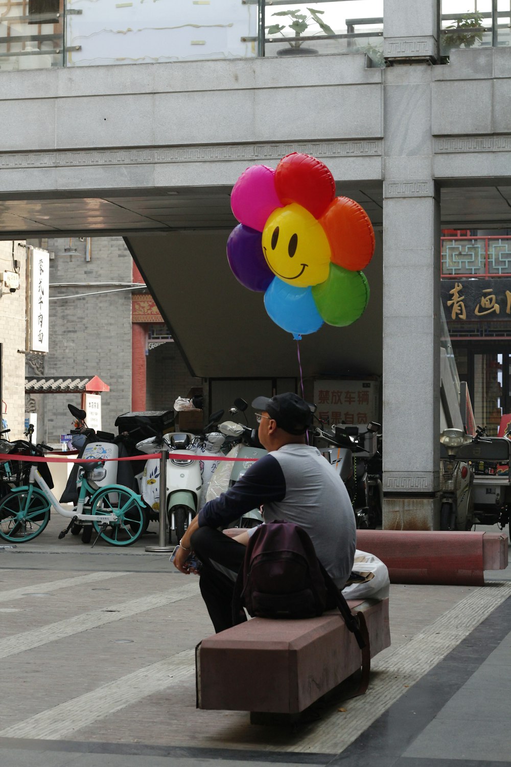 a man sitting on a bench with a bunch of balloons
